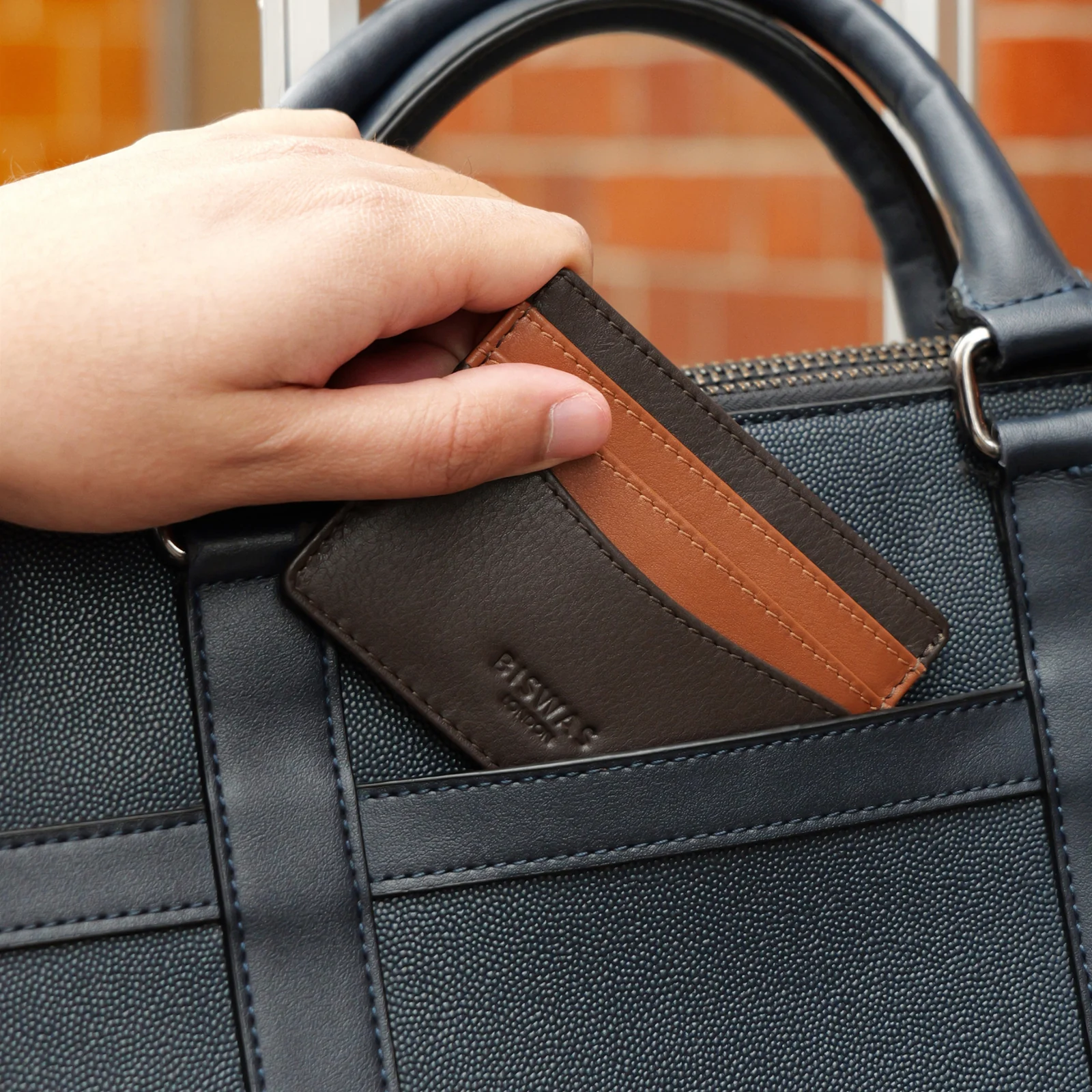 Espresso full-grain leather cardholder resting beside a work bag